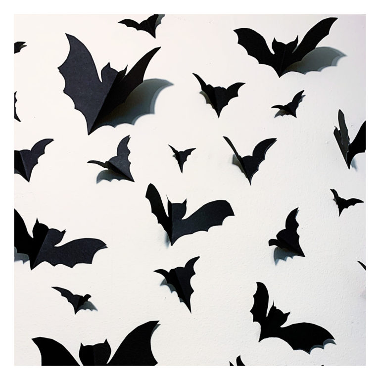 Subtle bat wall decor above a headboard in a cozy bedroom